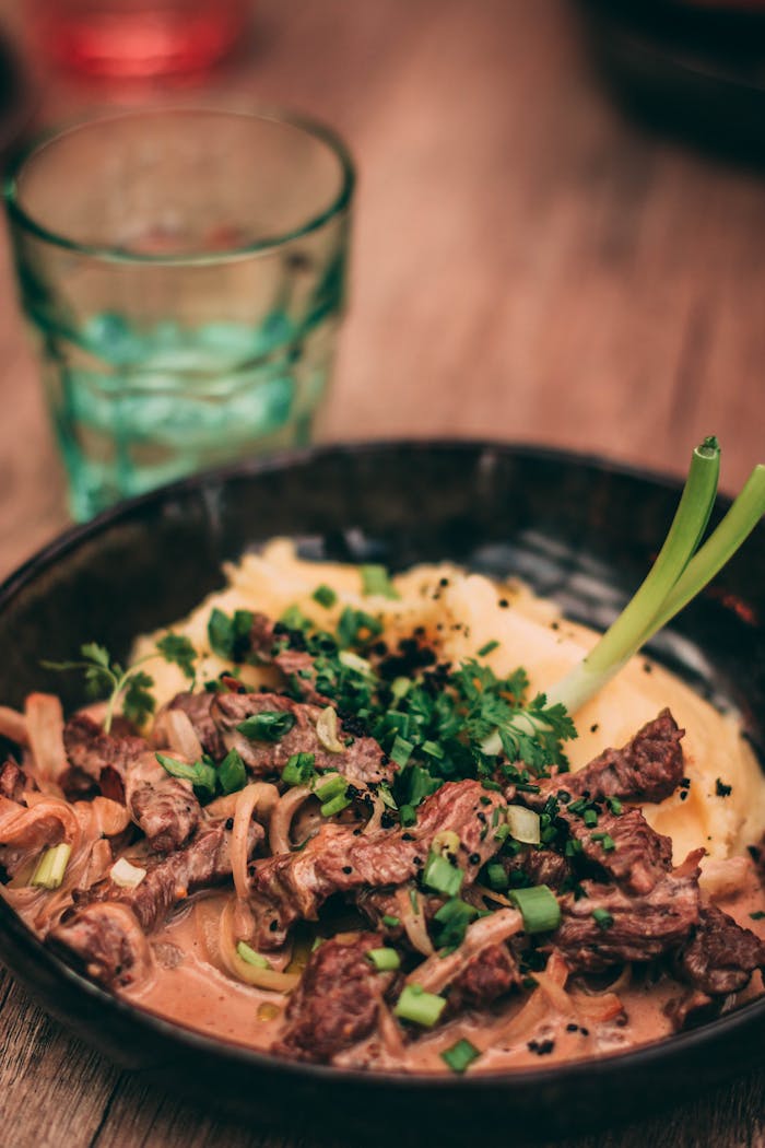 Delicious beef stroganoff served with creamy mashed potatoes, garnished with herbs.
