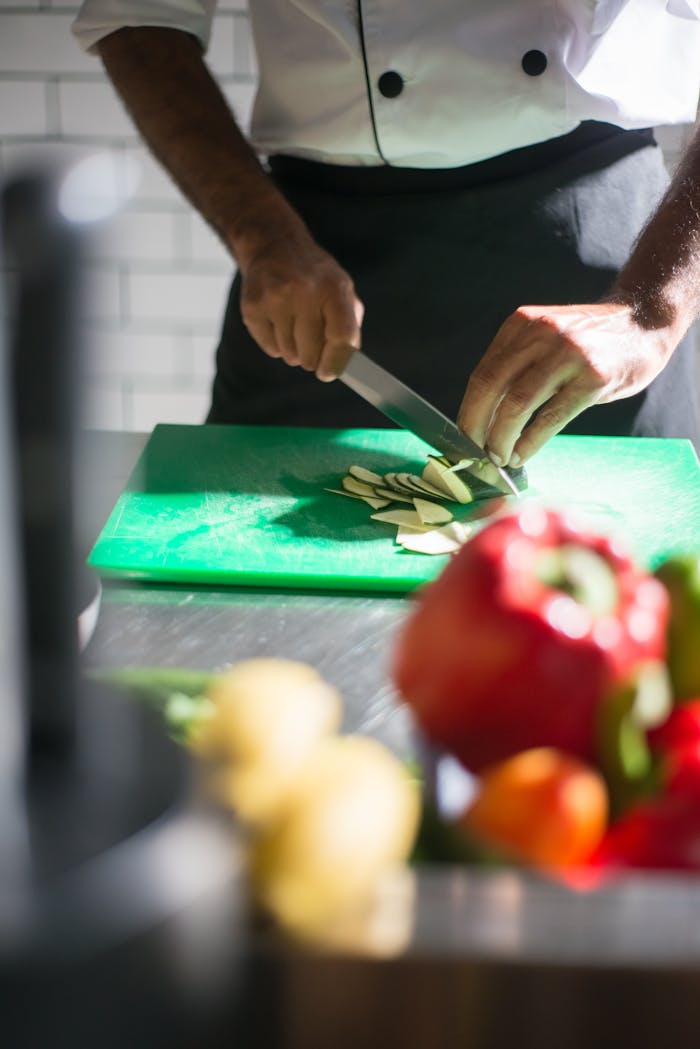 A chef expertly slices vegetables on a cutting board in a well-lit kitchen setting.